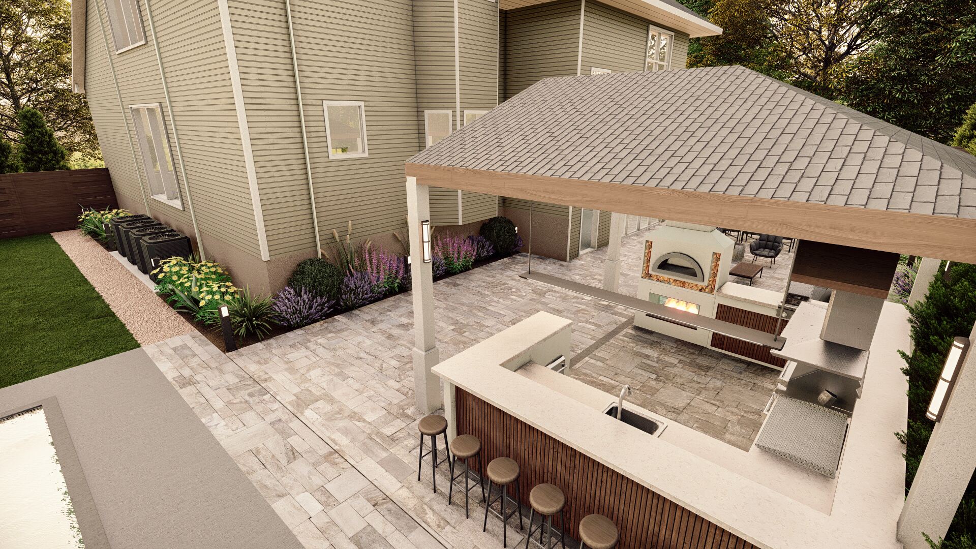 An elegant outdoor kitchen and dining area with a built-in pizza oven and grill, bar seating, and a cozy lounge space, all under a covered patio adjacent to a modern home, surrounded by lush flowering plants.